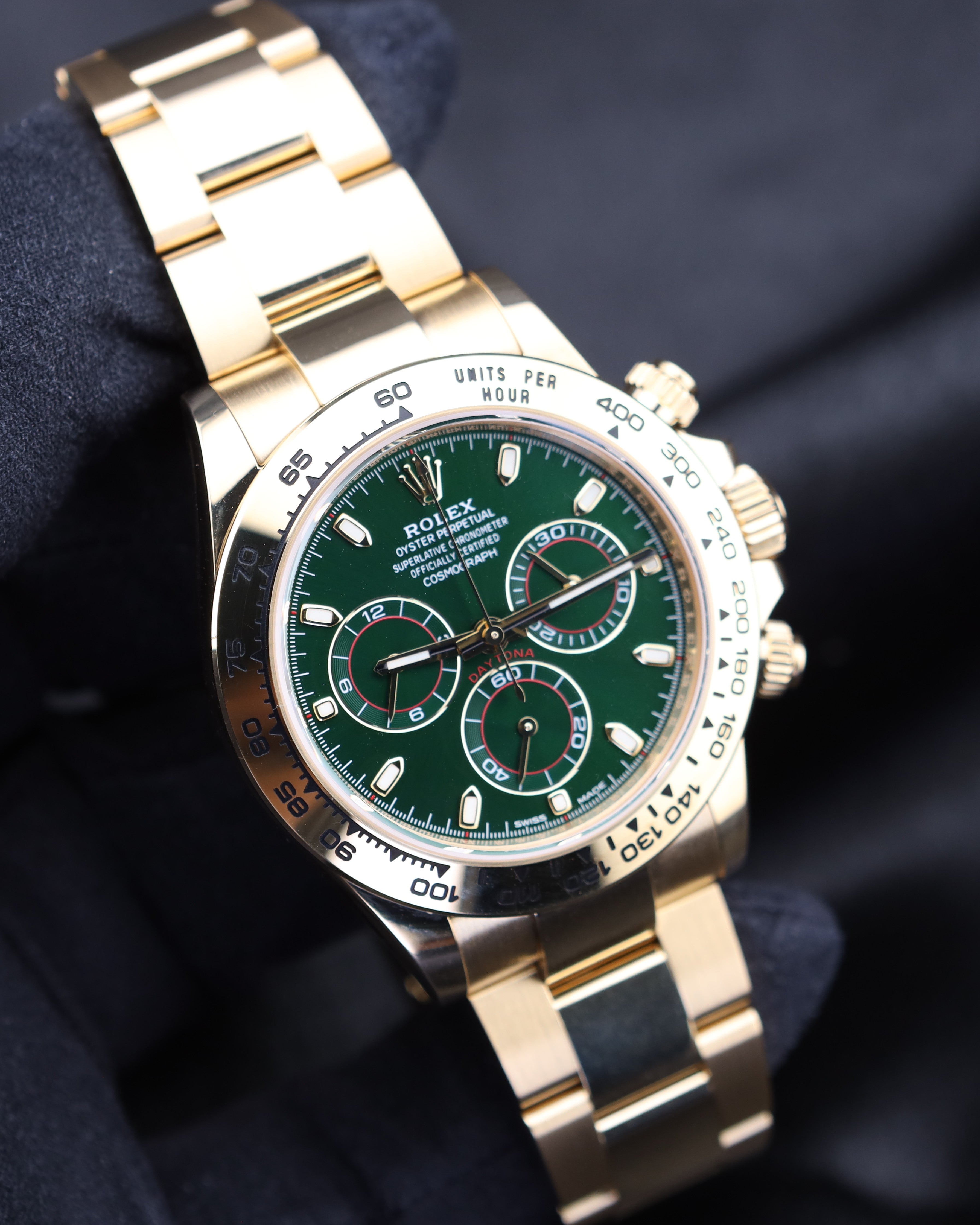 Gold watch with a green face on a dark background