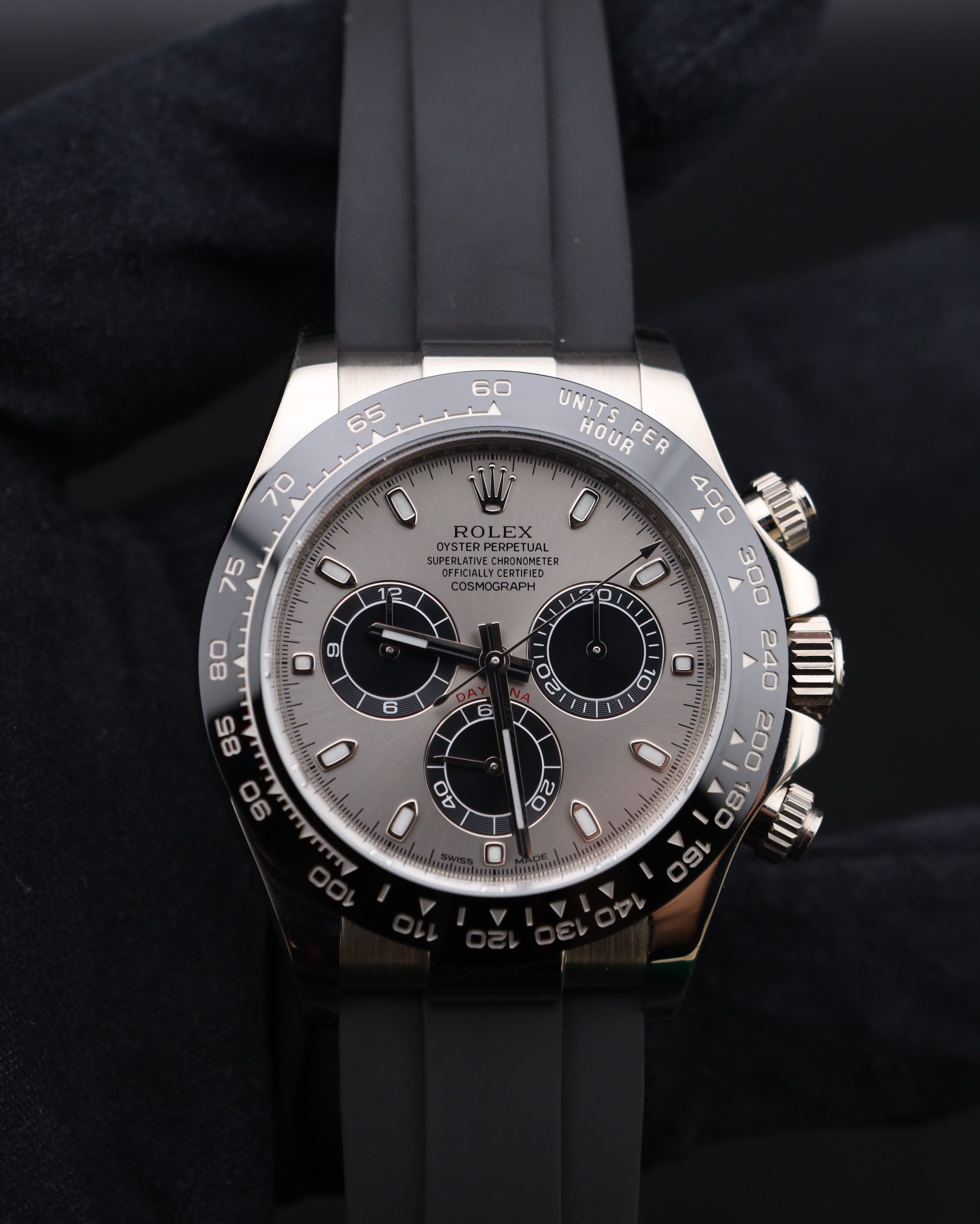 Rolex watch with silver case and black rubber strap on a dark background