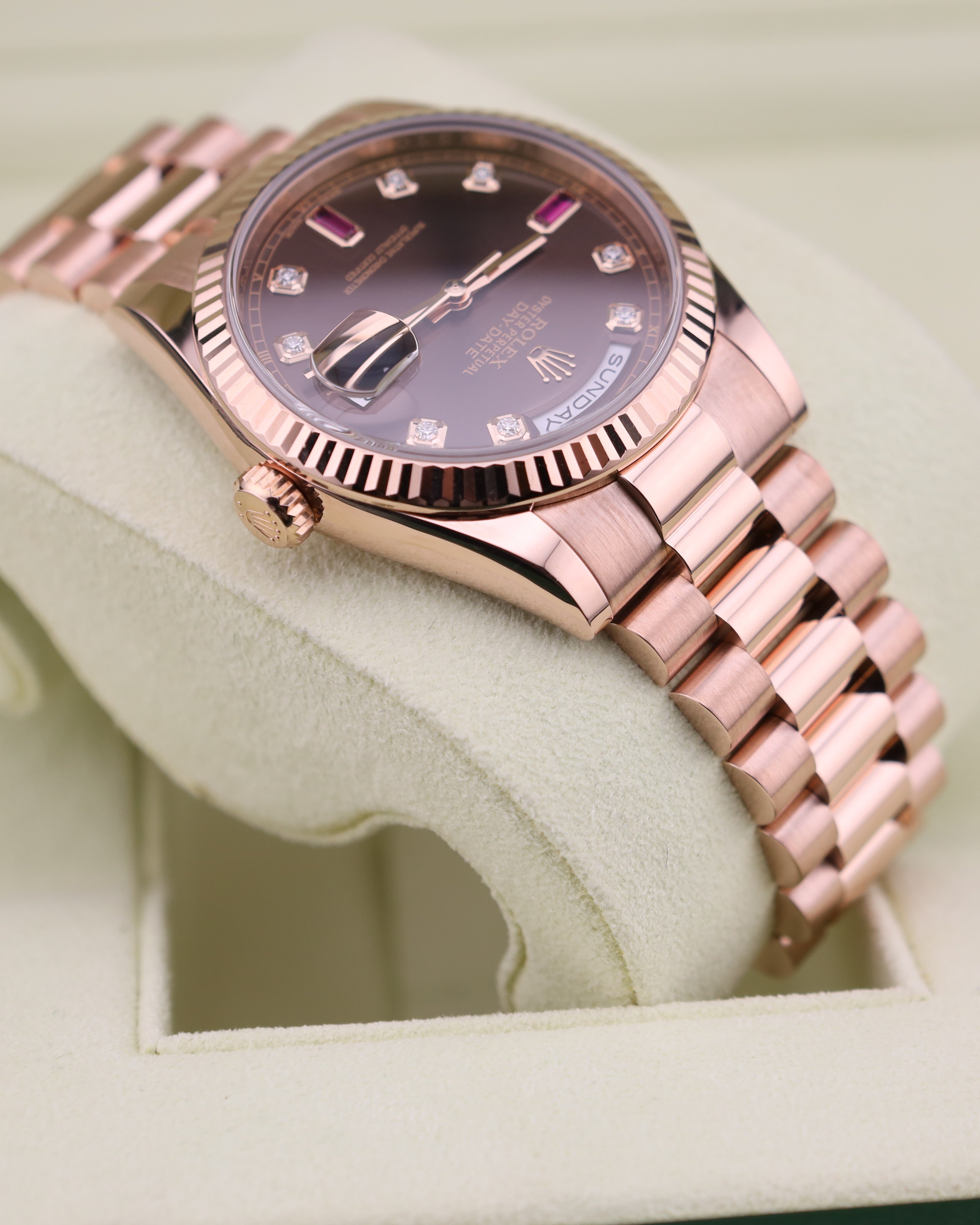 Rose gold watch with a detailed face on a light green cushion