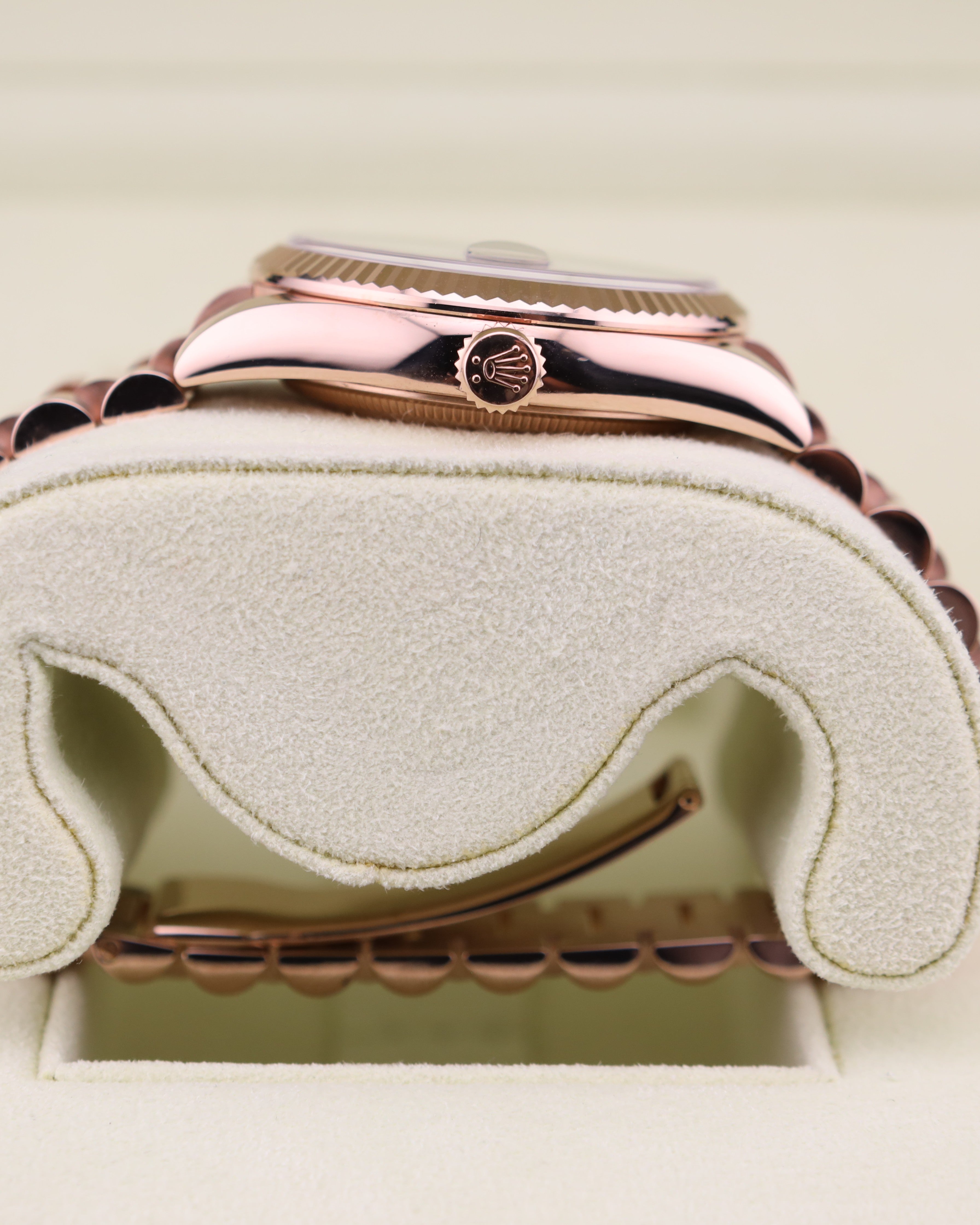 Rose gold watch with a visible brand logo on a beige cushion