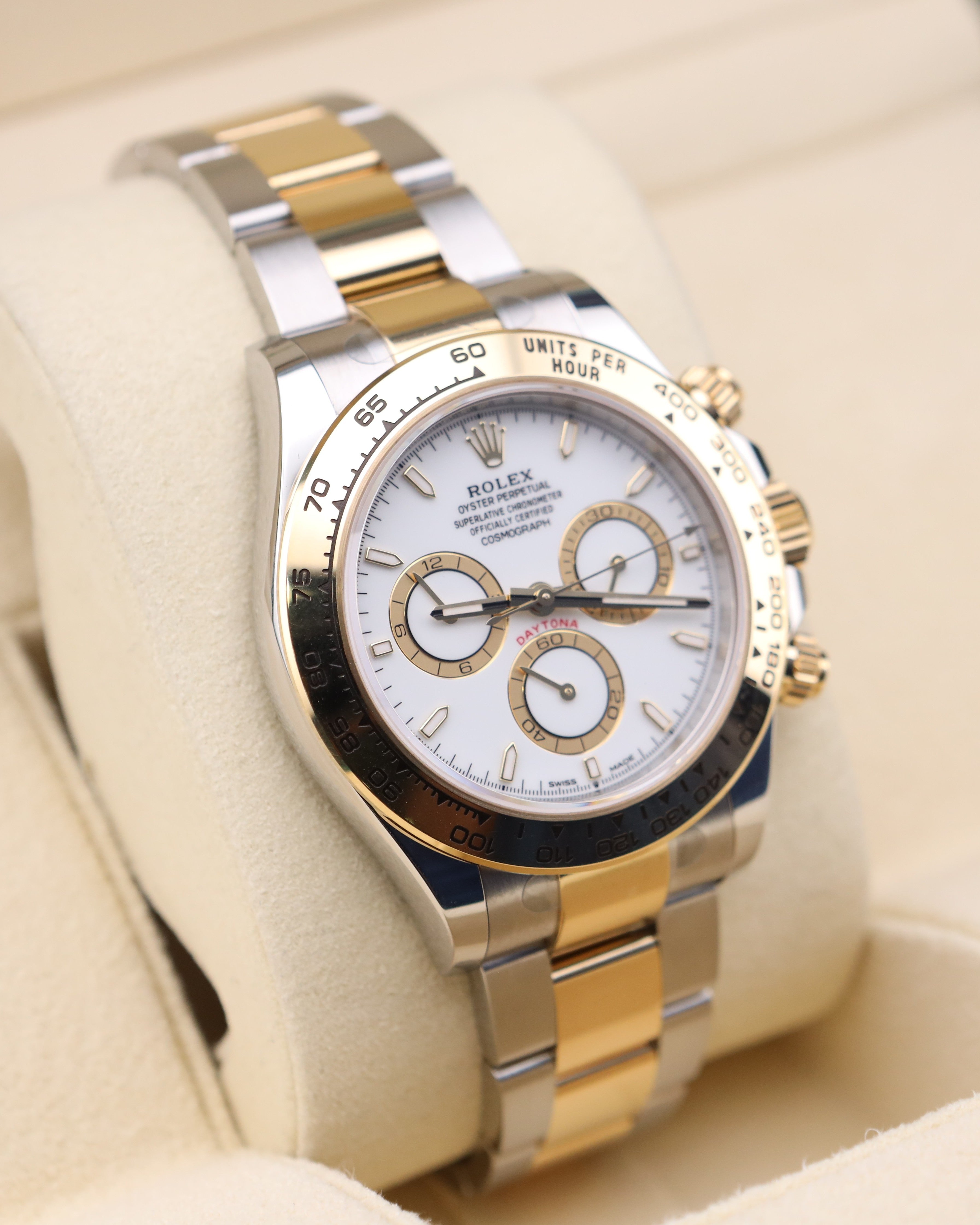 Luxury watch with a two-tone metal strap on a beige cushion