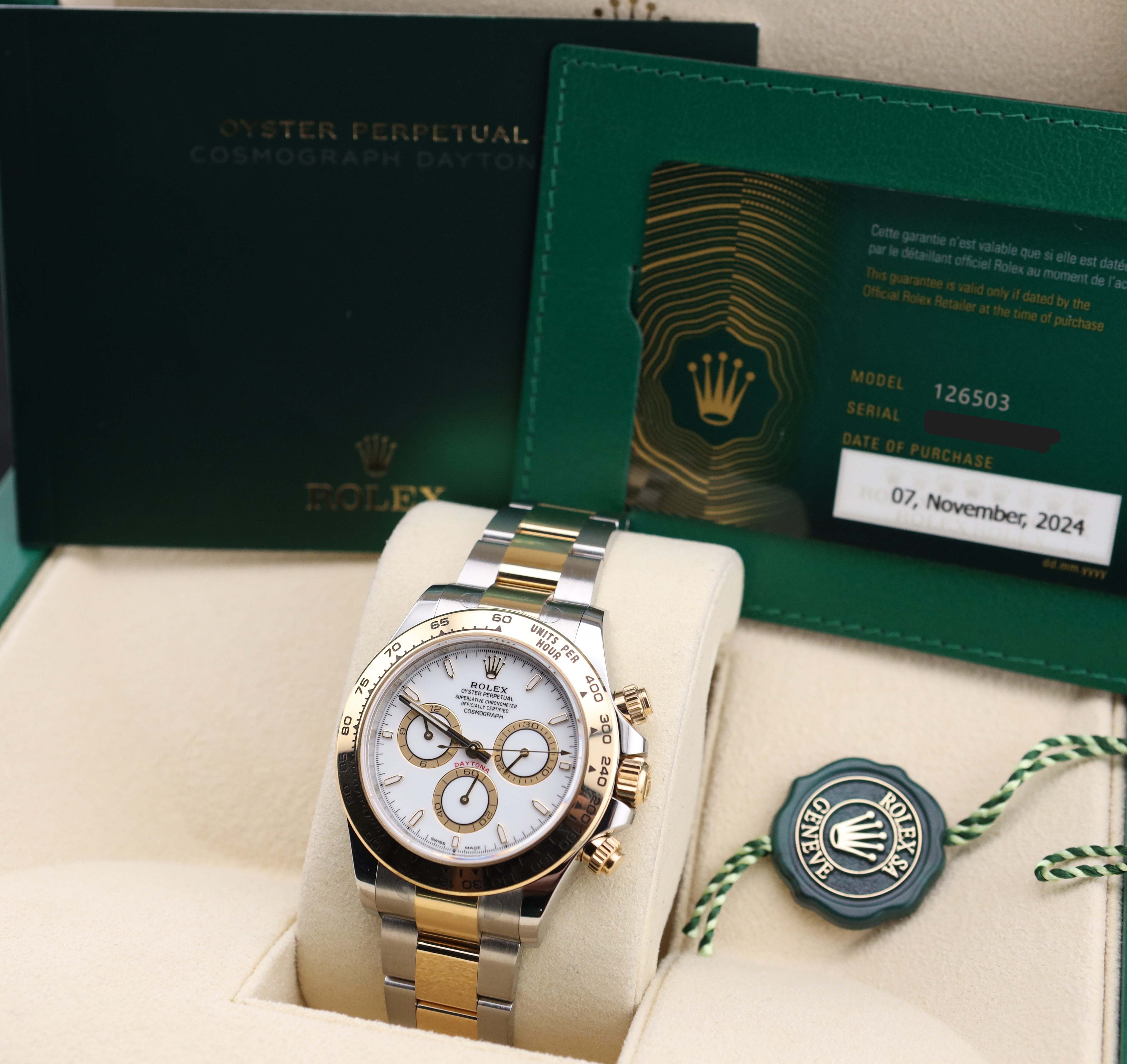 Rolex watch with packaging and certificate on a beige cushion