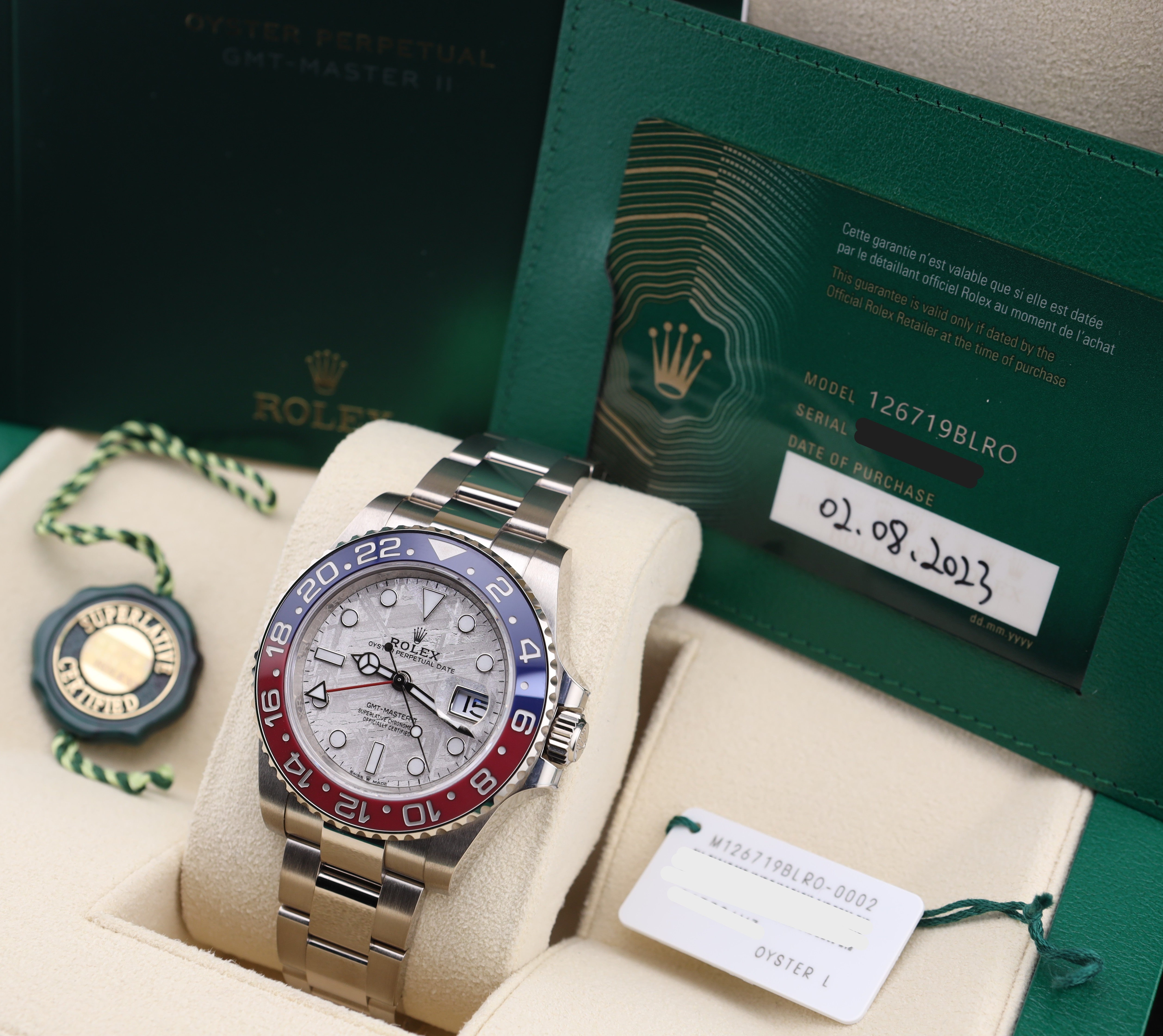 Rolex watch with packaging and card on a beige surface