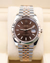 Rolex watch with brown dial and silver metal bracelet on beige cushion