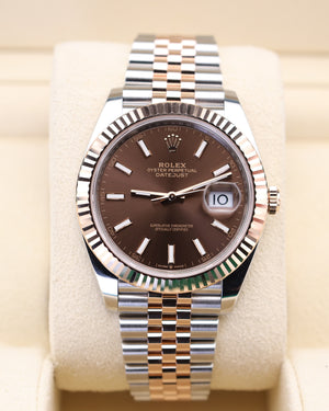 Rolex watch with brown dial and silver metal bracelet on beige cushion