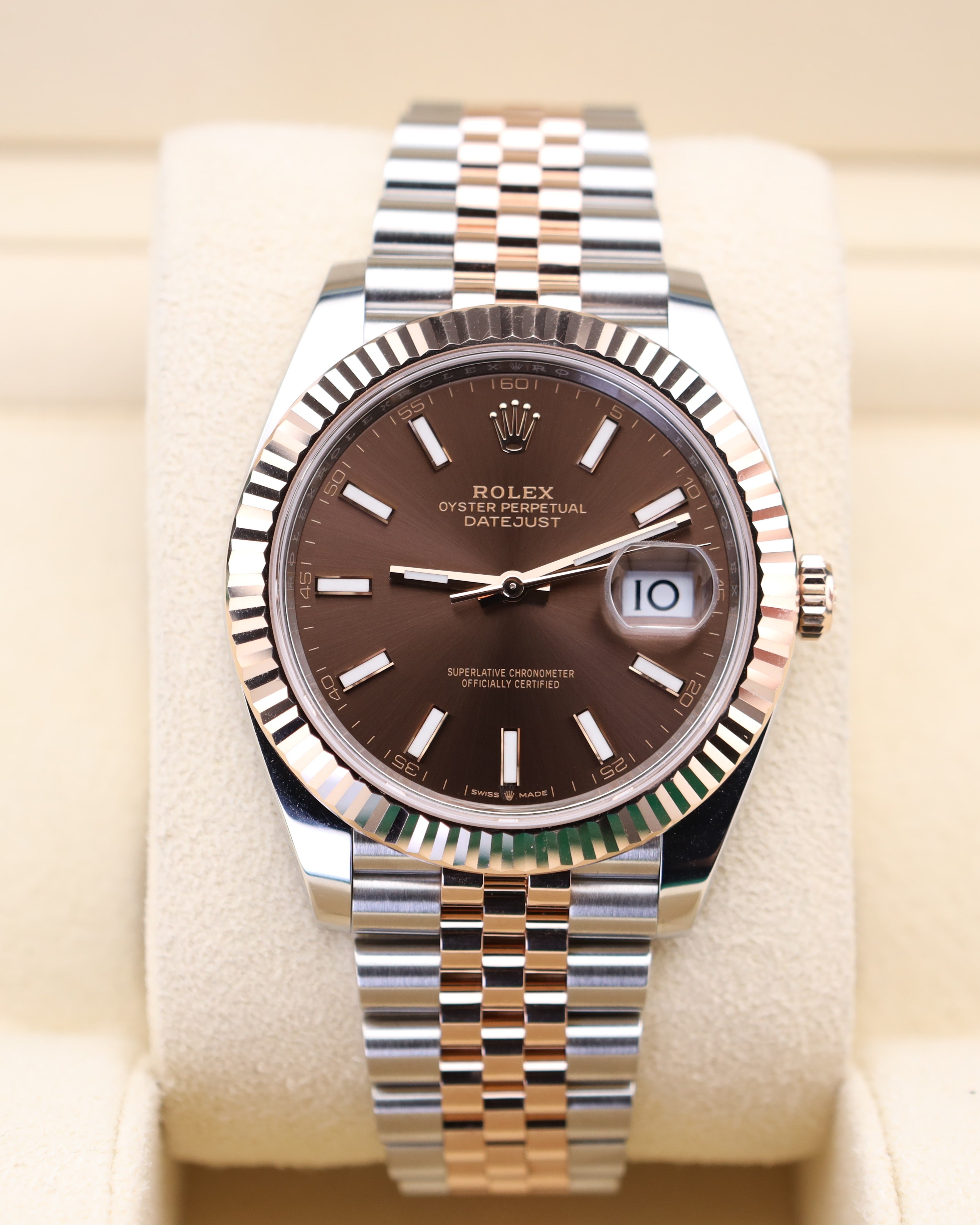 Rolex watch with brown dial and silver metal bracelet on beige cushion
